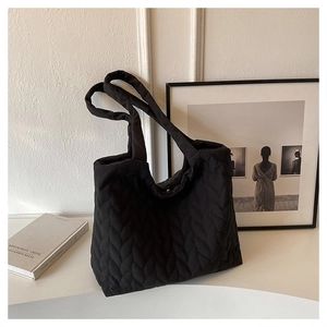Detail of black quilted puffer tote bag with V-shaped stitching and wide strap