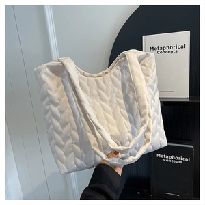 Detail of the soft quilted texture and leaf pattern on a large cream tote bag