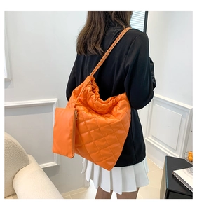 Detail showing orange quilted hobo bag with drawstring and matching coin purse on model