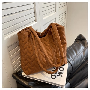 Detail of caramel brown quilted tote bag with braided texture and magnetic snap button