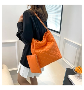 Detail of orange quilted shoulder bag with gold chain strap and matching coin purse