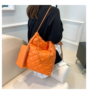 Detail of orange quilted tote bag with gold chain strap and detachable pouch