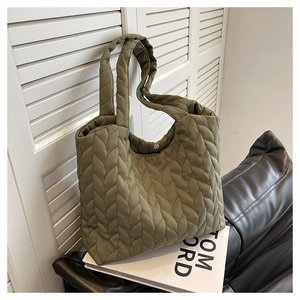 Detail of olive green quilted tote bag with leaf pattern texture and snap button closure