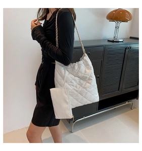Detailed view of white quilted tote bag with gold chain and matching mini pouch