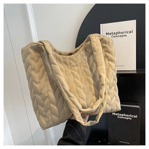 Close-up of large beige quilted tote bag showing soft nylon wave stitching and straps