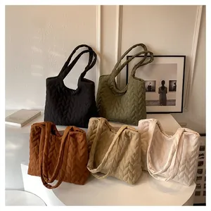 Multiple colors of large quilted leather tote bags displayed on a white tiered stand