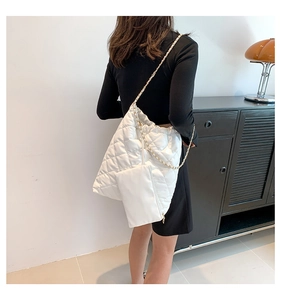 Detailed view of white quilted tote bag with gold chain strap and matching small pouch