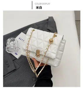 Close-up of cream quilted crossbody bag with gold chain strap and metal lock detail