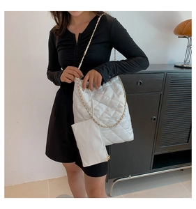 Detail of white quilted tote bag with chain strap and matching small zipper pouch