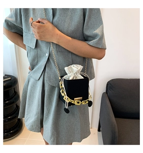 Close-up of black textured bucket bag with gold chain and drawstring inner pouch details