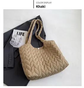 Top view of khaki quilted tote bag featuring chevron texture on grey blazer background