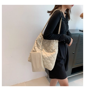 Detail of beige quilted tote bag featuring chain straps and matching zipper pouch