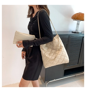 Detail of quilted tote bag with golden chain strap and matching small zipper pouch