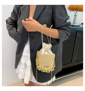 Detail of straw woven bucket bag with gold chain and white drawstring lining
