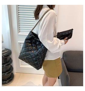 Detail of black quilted leather bucket bag with gold chain strap and matching pouch