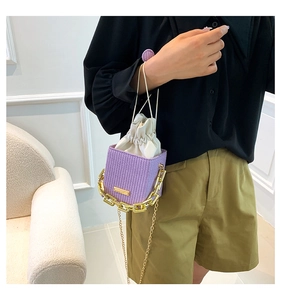 Detailed close-up of a purple woven mini bucket bag with gold chain strap on a model