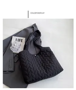 Close-up of black quilted tote bag showing intricate wave pattern and wide shoulder strap