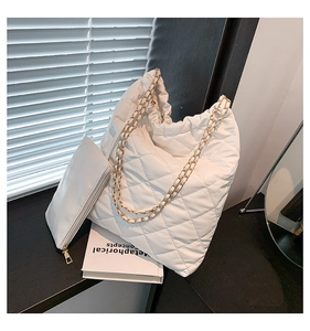 Detail of white quilted tote bag with golden chain strap and matching zipper pouch