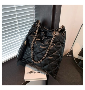 Close-up of black quilted tote bag with golden chain strap and small zip pouch on side