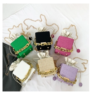 Detail view of woven texture mini square bags with chunky gold chains and drawstring lining