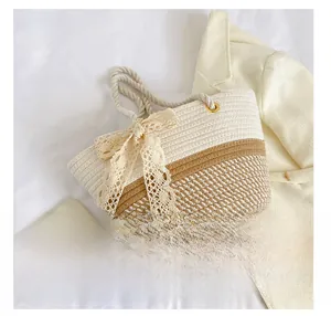 Detail view of woven shoulder bag with beige lace bow and thick rope handles on white fabric