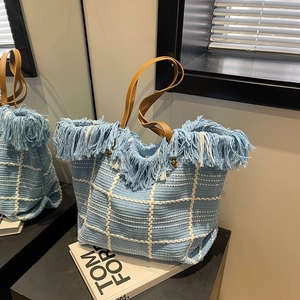 Blue and white woven checkered tote bag with fringe trim and brown leather handles