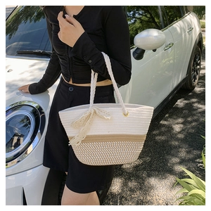 Detail of woven tote bag featuring bicolor rope design and delicate lace bow ornament