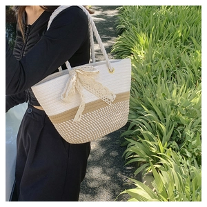 Detail of woven tote bag with cream lace bow and contrast stitching on a summer day