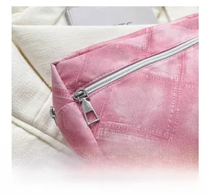 Gros plan sur la fermeture éclair argentée et le tissu texturé rose de ce sac de voyage