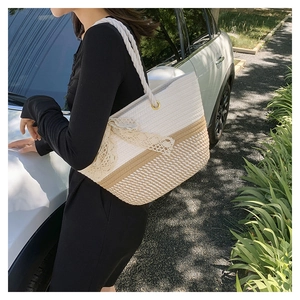 Detail of woven tote bag with beige lace bow and cotton rope handles for summer style