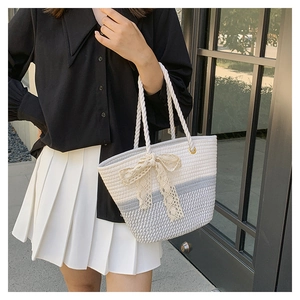 Detailed shot of a two-tone woven tote bag with lace bow and thick rope handles