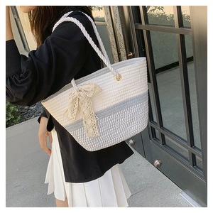 Detail of woven tote bag with cotton rope handles and decorative beige lace bow