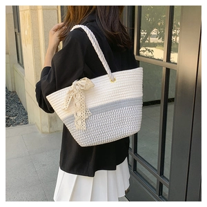 Detail of woven tote bag with bicolor stripes, lace bow, and thick rope handle style