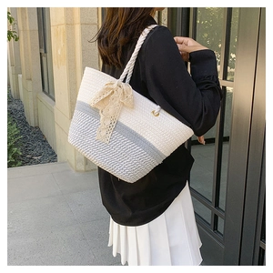 Detail of woven tote bag with beige lace bow and golden metal grommet rings