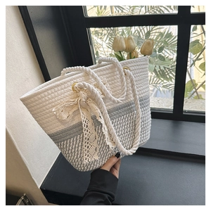 Detail of woven tote bag with lace bow decoration and premium metal ring attachment