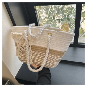 Detail of woven tote bag featuring white contrast panels and a delicate lace bow accent