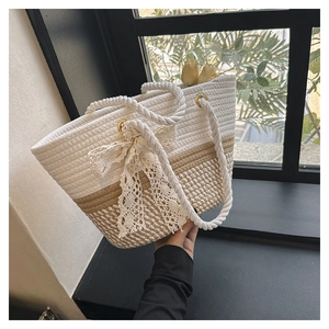 Close-up of woven straw tote bag with lace bow detail and sturdy cotton rope handle