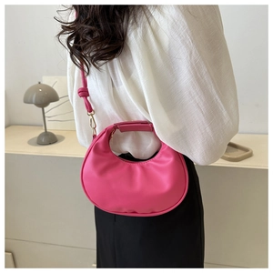 Sac hobo croissant fuchsia minimaliste porté par un modèle dans un intérieur moderne