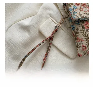 Close-up of floral fabric wrist strap with a premium light gold metal lobster clasp