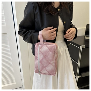 Gros plan du sac à main en velours matelassé rose avec dragonne et fermeture éclair argent