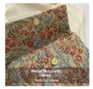 Close-up of golden magnetic snap closure on vintage floral embroidered envelope bag