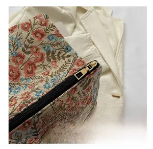 Detail of floral jacquard fabric texture and smooth gold metal zipper on clutch