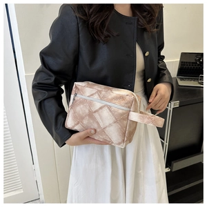Détail de pochette de voyage à carreaux avec fermeture éclair argentée par un mannequin