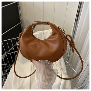 Détail du sac croissant marron chaud avec zip doré et texture en cuir lisse