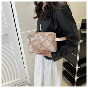 Détail de la pochette beige à motifs géométriques avec fermeture éclair et poignée