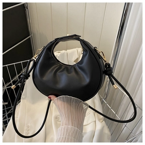 Détail du sac croissant en cuir noir avec zip doré et bandoulière nouée élégante