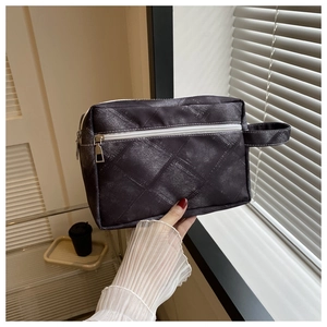 Détail de la trousse de toilette grise à carreaux avec fermeture éclair et poignée latérale