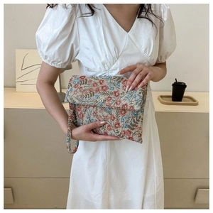 Detail of floral tapestry evening clutch with metal clover clasp and wrist strap