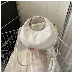 Gros plan du sac demi-lune blanc montrant la texture du cuir et détails dorés