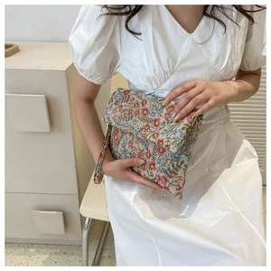Detail of floral jacquard clutch bag with golden clover clasp and wrist strap